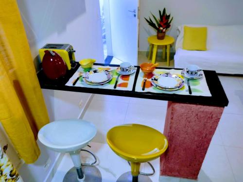 瓜鲁雅Flat Ideal Guarujá - Apto Studio Mobiliado, Ar-Condic e Cozinha Completa的桌子,桌子上放有盘子,杯子和椅子