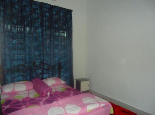 加央Pertama Homestay的一间卧室配有粉红色的床和蓝色窗帘