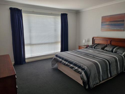 巴瑟尔顿Busselton Broadwater Holiday Home的一间卧室配有床和蓝色窗帘的窗户