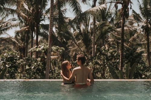 塞莱马德加Kusfarm Bali的坐在游泳池里的男人和女人