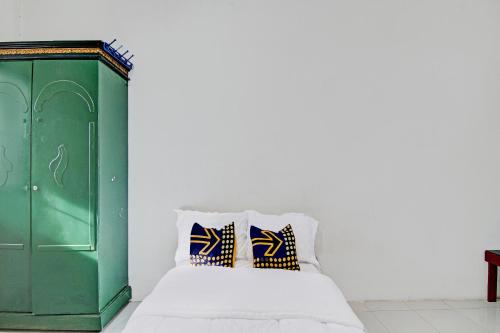 BangkinangSPOT ON 91950 Guest House TekNong Syariah的一张带绿色橱柜的床和两个枕头
