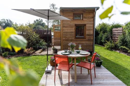 谬克Zirbenholz Tiny House "Waldhauszeit" am See的花园的遮阳伞下的桌椅