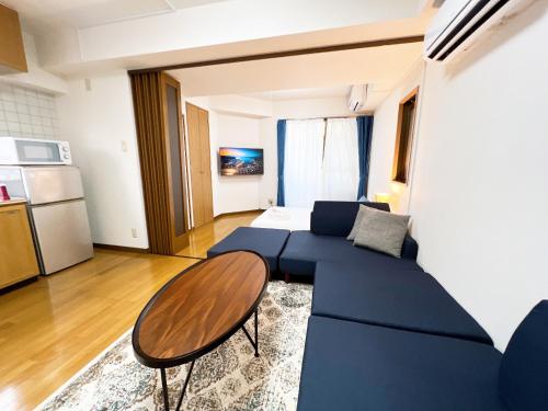 广岛PINE TREE HOTEL的客厅配有蓝色的沙发和桌子