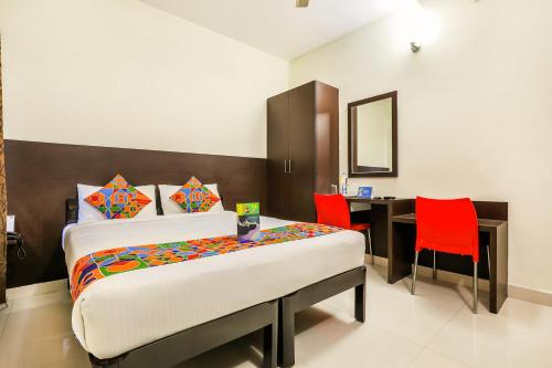 班加罗尔FabHotel RMS Comforts Yeshwantpur的一间卧室配有一张床和一张带红色椅子的桌子