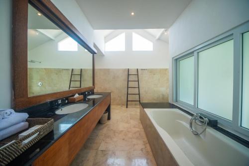 KetewelSuzuki Villa Ketewel Beachfront的浴室配有2个盥洗盆、浴缸和大镜子