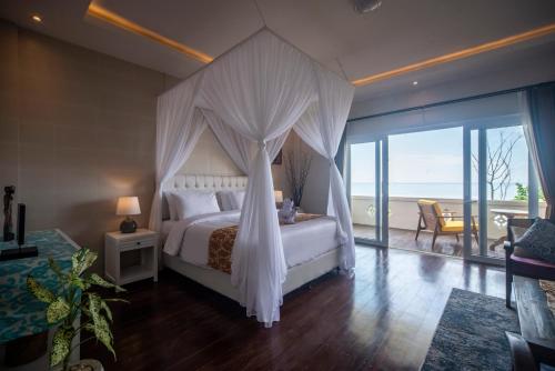 KetewelSuzuki Villa Ketewel Beachfront的一间卧室设有一张天蓬床和一个阳台
