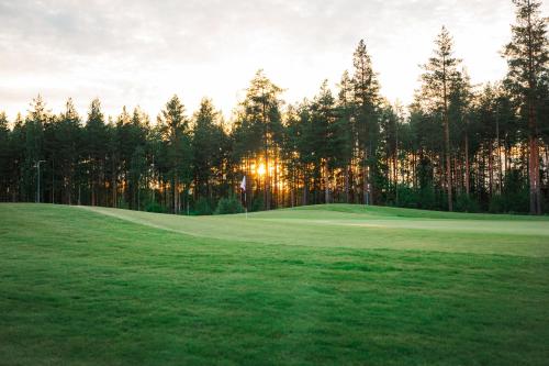 伊马特拉Holiday Club Saimaa Apartments的树木后面的高尔夫球场,阳光照耀
