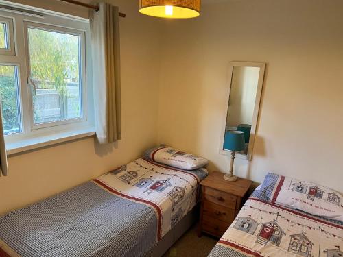 海景城2 Bedroom Bungalow SV58, Seaview, Isle of Wight Free Wi-Fi的一间卧室配有两张床和镜子