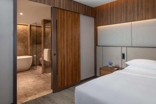 特里凡得琅Hyatt Regency Trivandrum的一间卧室配有一张床,浴室设有浴缸
