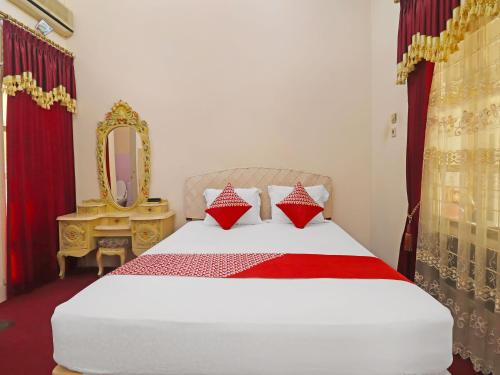 占碑市OYO 2899 Ardilia Bandara Syariah的一间卧室配有一张带镜子的床和一张四柱床