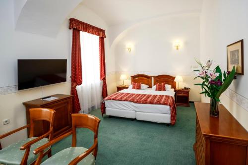 RöjtökmuzsajSzidónia Castle的酒店客房带一张床、一张桌子和椅子