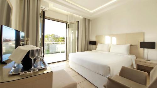 波利克罗诺Akrogiali Exclusive Hotel (Adults Only)的酒店客房,配有床和电视
