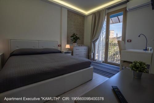 恩纳ROCCA DI CERERE Self Check-in Apartments的一间卧室配有一张床、一张书桌和一个窗户。