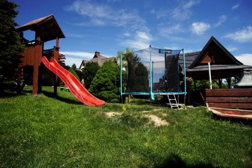 考斯赛力克Górski Pałacyk Kompleks obiektów的草地上带红色滑梯的游乐场