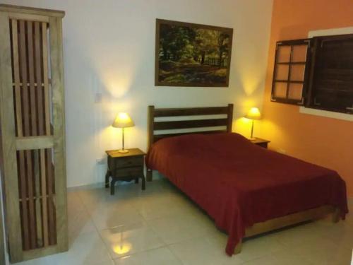 伊利亚贝拉Chalés Azuleto - Ilhabela的一间卧室配有一张红色的床和两盏灯。