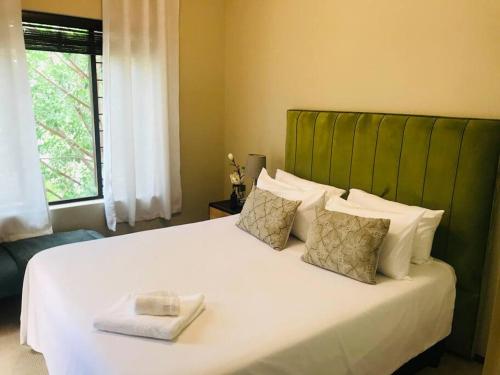 SandtonPerfectly located beauty in secure Estate的一间卧室配有一张白色大床和绿色床头板
