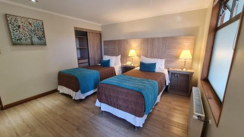 康塞普西翁Hotel D&V Concepción的酒店客房设有两张床和两盏灯。