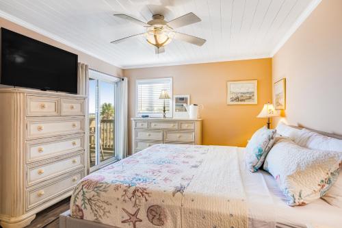 费南迪纳比奇Sand Dollar Villas 109的一间卧室配有一张床和一个带平面电视的梳妆台。
