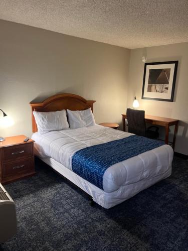 林垦Travelodge by Wyndham Lincoln Northeast的酒店客房设有一张大床和一张书桌。