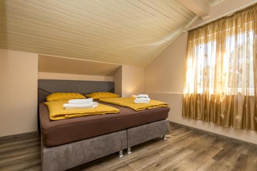 木洛希尼Rooms with a parking space Mali Losinj (Losinj) - 9681的一间卧室配有一张带黄色床单的床和一扇窗户。