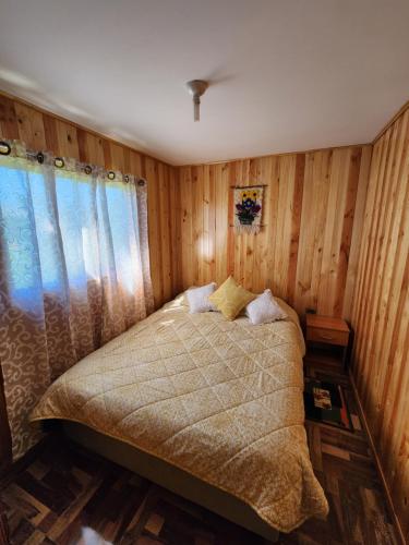 San José de la MariquinaCabaña Nuevo Amanecer的一间卧室配有一张带木墙和窗户的床。