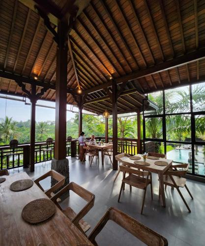 吉安雅Pinggala Villa Ubud的餐厅设有木桌、椅子和窗户。