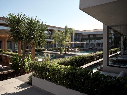 蒂锡利维Contessina Suites & Spa - Adults Only的享有带游泳池和棕榈树的建筑的外部景色
