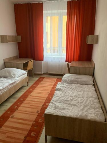 Moldava nad BodvouHostel SOS Moldava的客房设有两张床和一个带红色窗帘的窗户。