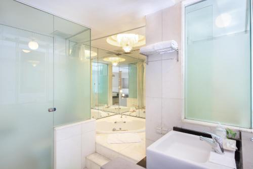玛琅Lux Tychi Hotel的浴室配有水槽、淋浴和浴缸。