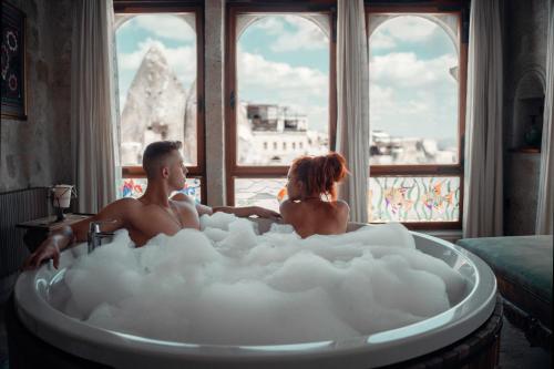 格雷梅苏丹洞穴套房酒店的男人和女人坐在浴缸里,浴缸里充满泡沫