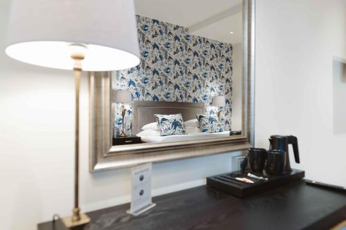 赫尔辛基Hotel Bastian的一间设有镜子和一张带台灯的桌子的房间