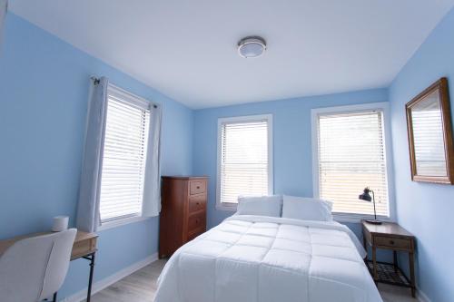 杰克逊维尔海滩Central & Comfortable Home Walk to the Beach!的蓝色的卧室设有床、书桌和窗户