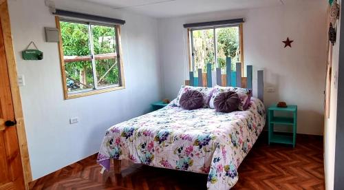 安加罗阿Henua Roa Loft的一间卧室配有一张带被子的床和两个窗户
