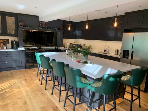 欣德黑德Stunning Surrey Hills Country House set in half an acre的厨房配有大型白色桌子和绿色椅子