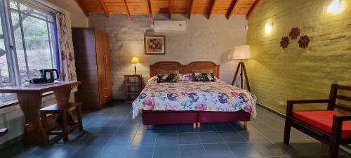 科塔德拉斯Hostal La Quebrada的卧室配有1张床、1张桌子和1把椅子