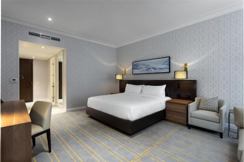 多伦多Sutton Place Hotel Toronto的酒店客房,配有一张床、一张桌子和椅子