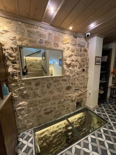 约阿尼纳VIRSA BOUTIQUE ROOMS的石墙上的大镜子,带游泳池