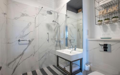 基拉尼Hotel67的带淋浴和盥洗盆的白色浴室