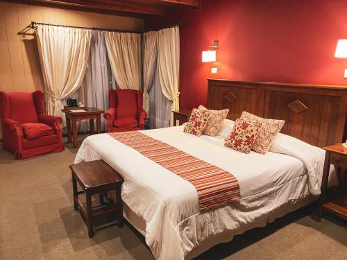 埃尔卡拉法特拉卡提亚精品酒店的一间卧室配有一张大床和两张红色椅子