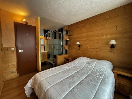 里蒙纽耶Appartement Les Menuires, 2 pièces, 4 personnes - FR-1-452-177的一间卧室设有一张床和木墙