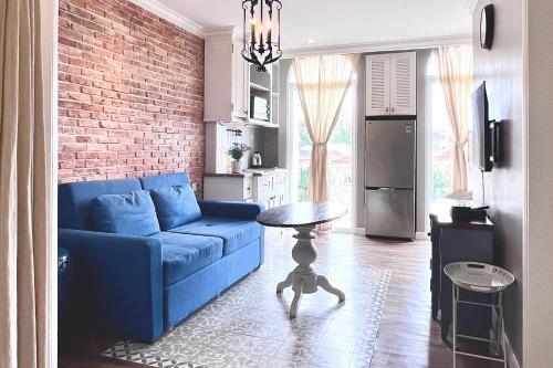 胡志明市HOME by FLATTO APARTMENT的客厅设有蓝色的沙发和砖墙