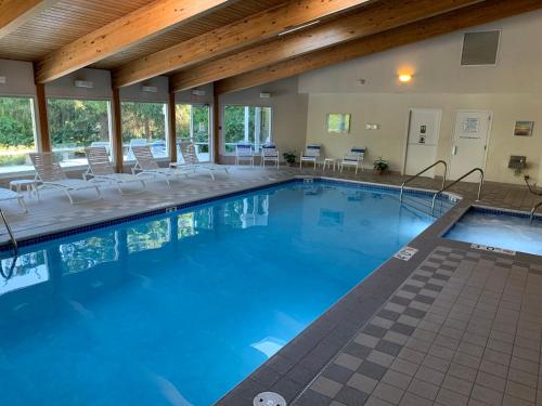 鱼溪AppleCreek Resort-Hotel & Suites的大楼内带桌椅的大型游泳池