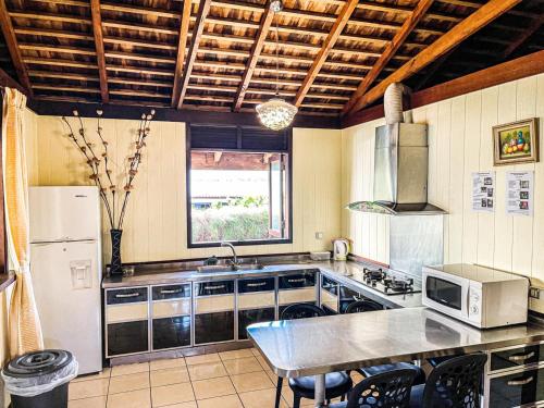 TemaeMOOREA - The Golden Reef Bungalow Nuku Hiva的厨房配有冰箱和带微波炉的桌子。