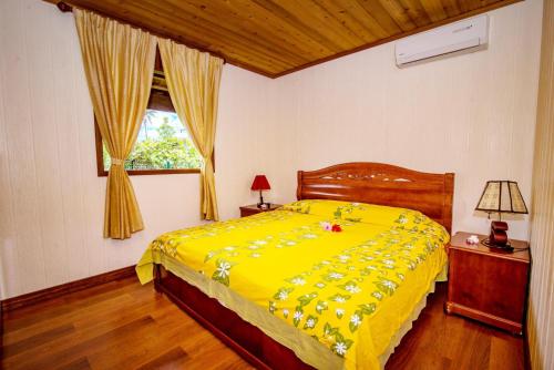 TemaeMOOREA - The Golden Reef Bungalow Nuku Hiva的卧室里的一张黄色的床,卧室里设有窗户