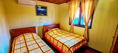 TemaeMOOREA - The Golden Reef Bungalow Bora Bora的一间卧室设有两张床和窗户。
