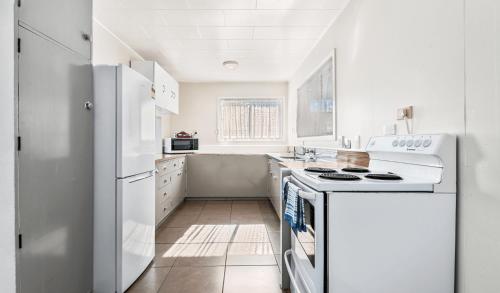 罗托鲁瓦Kowhai Motel Rotorua的白色的厨房配有炉灶和冰箱。