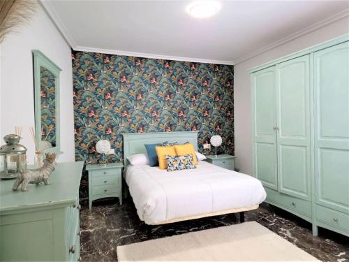 哈恩Piso-Loft COS Centro Jaén 2的一间卧室配有一张带蓝色橱柜和壁纸的床。