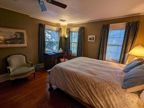 格林斯伯勒English Cottage的一间卧室配有一张床、一把椅子和窗户。