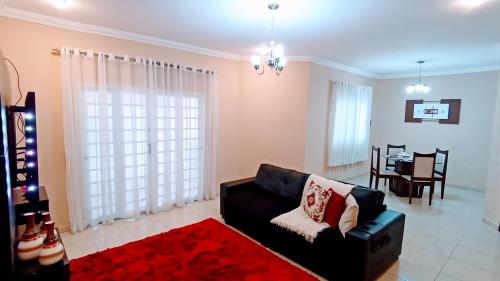 陶巴特Casa Confortável, 3 Quartos, Ar Condic. 300 Mega, Taubaté的客厅配有黑色沙发和红色地毯。