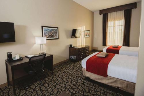 MadisonBest Western Plus Lakeview Hotel的酒店客房设有两张床、一张桌子和一台电视。